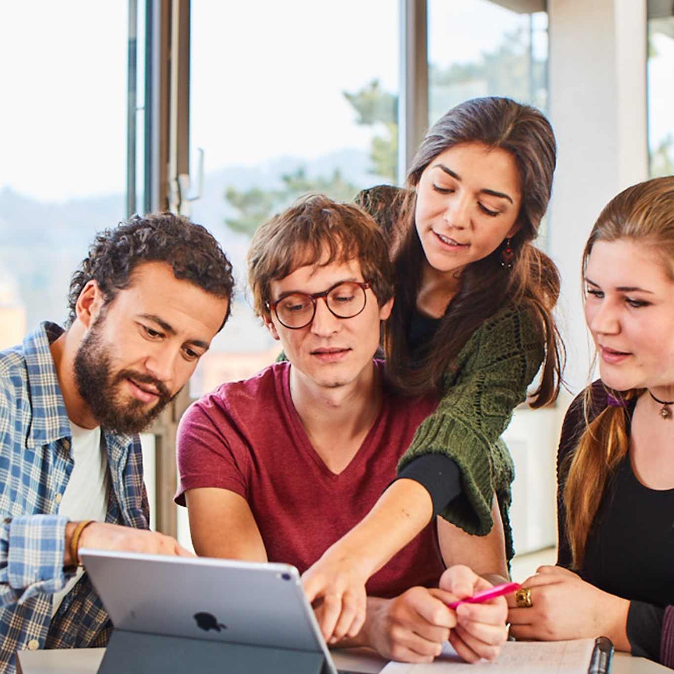 Studierende sitzen in einer Gruppe um ein Notebook